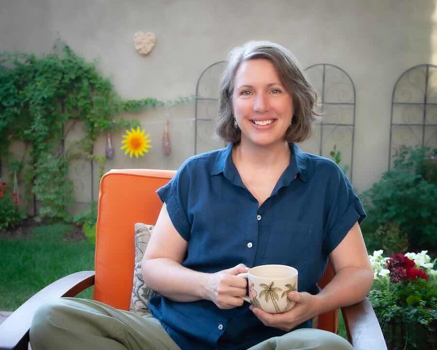 Smiling woman holding mug in sunny garden patio