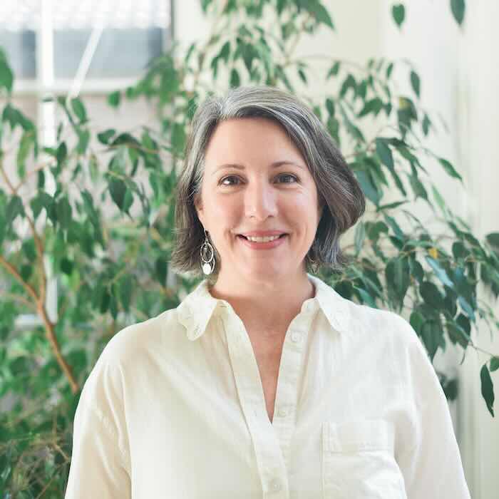 Smiling woman in white blouse, indoor plants background.