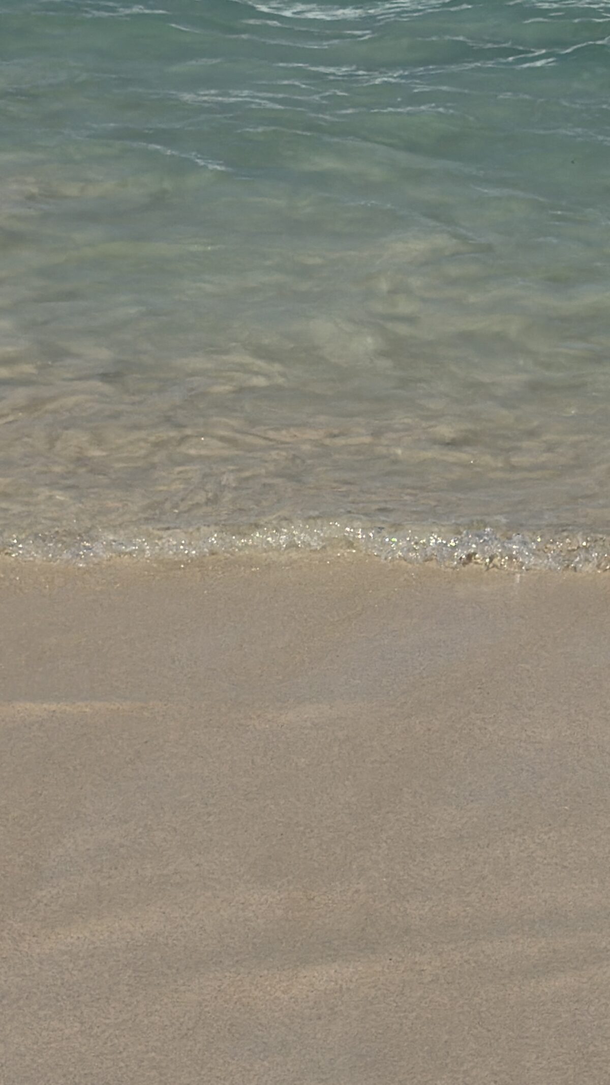 Gentle ocean waves washing onto sandy beach