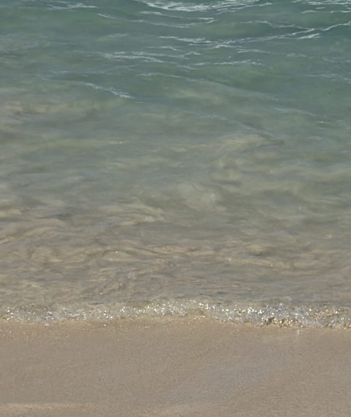 Gentle ocean waves washing onto sandy beach