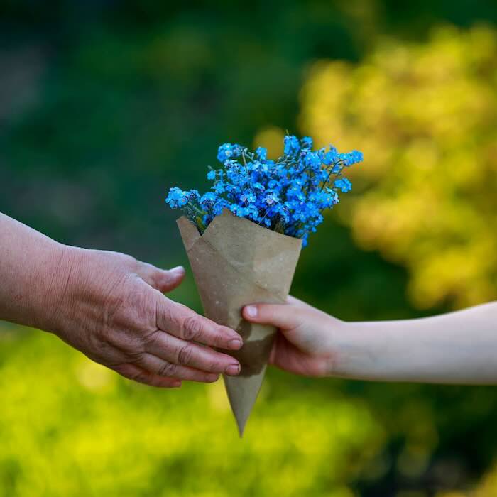 Hands exchanging bouquet of blue flowers