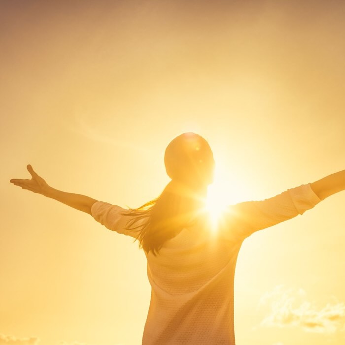 Woman embracing sunlight with open arms